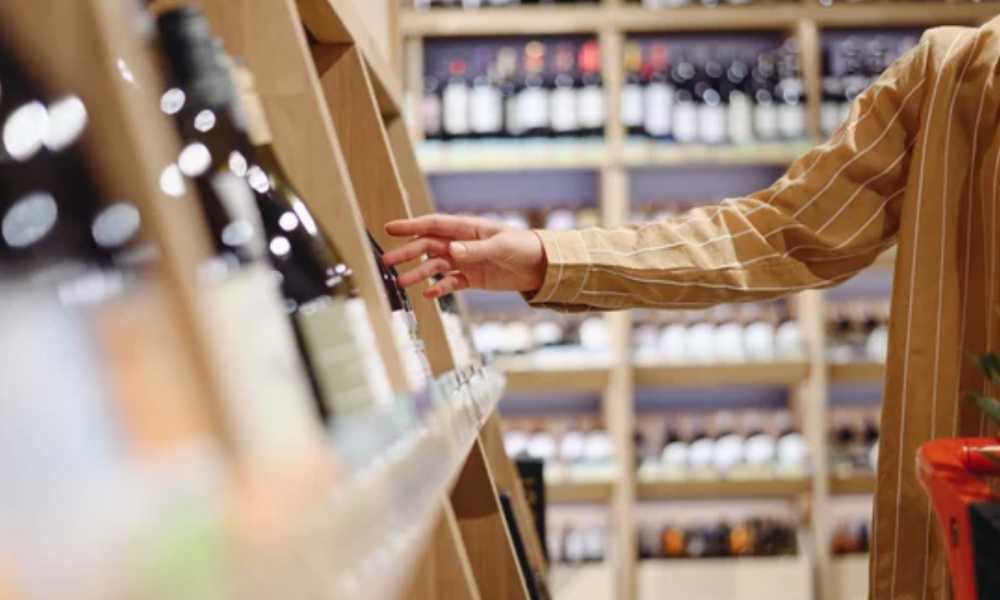 Person's arm choosing wine in an aisle