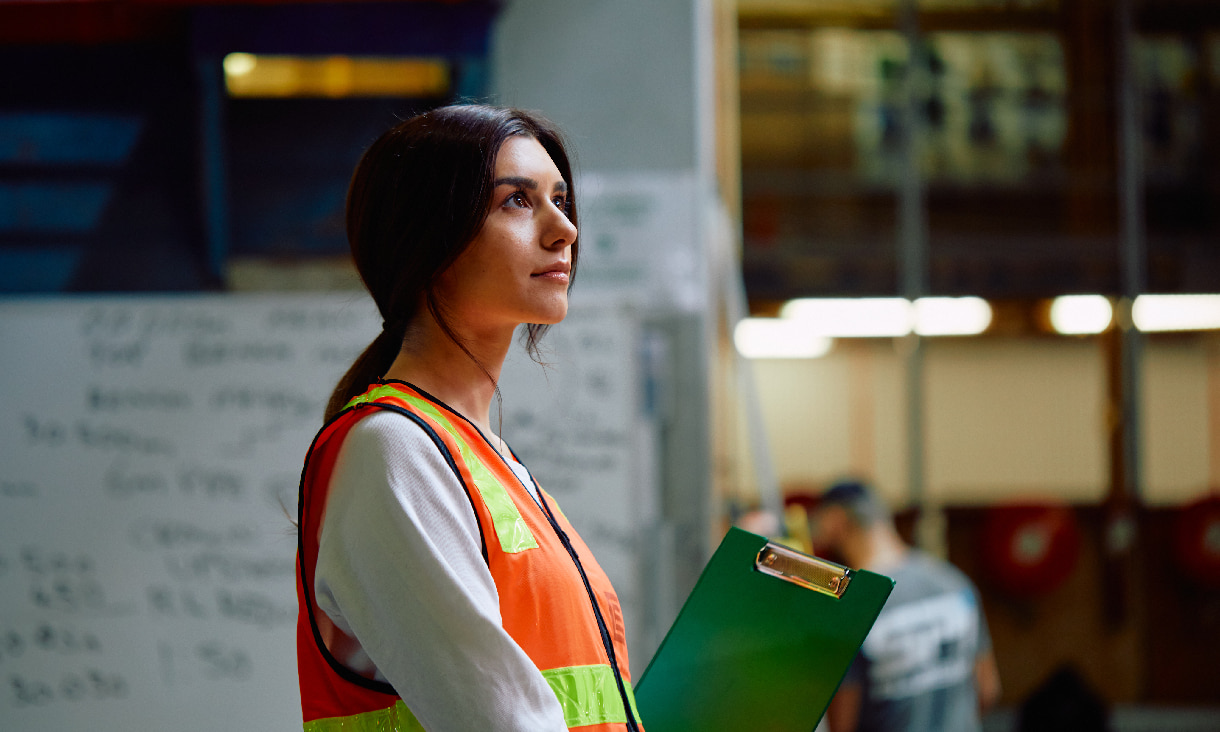 Female student wearing fluorescent vest, holding clipboard
