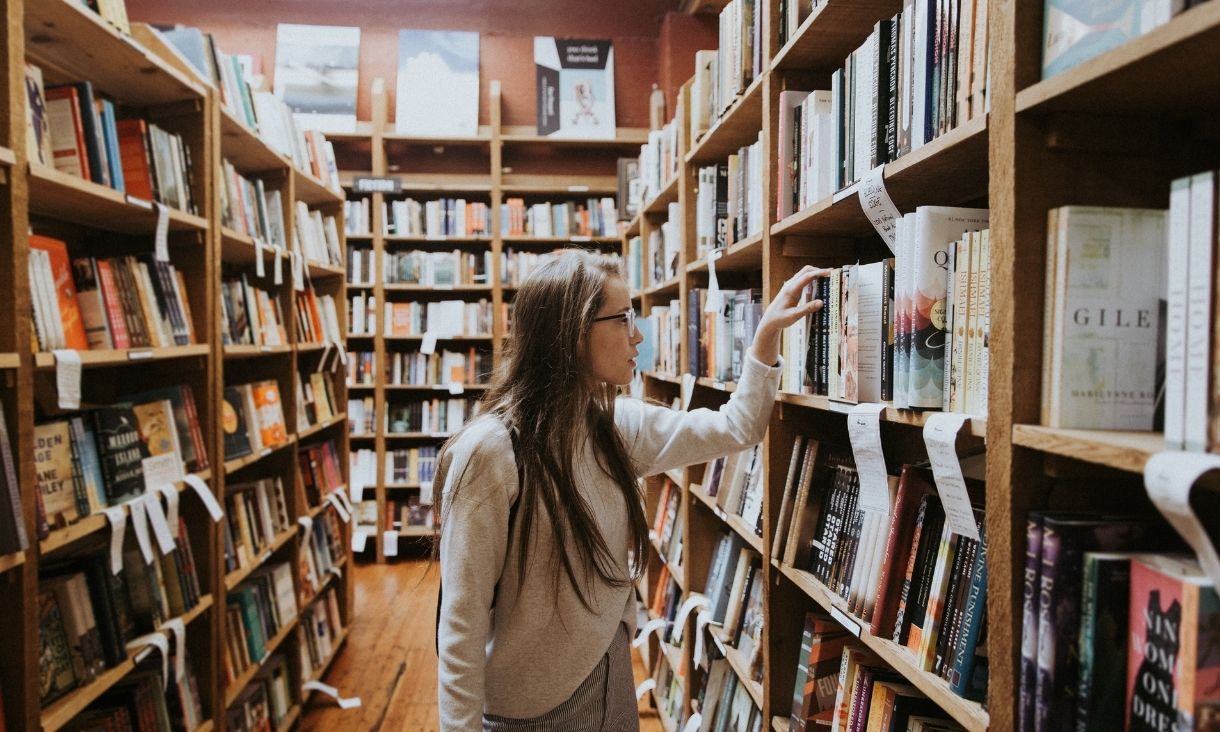 A woman walks in a bookshop.