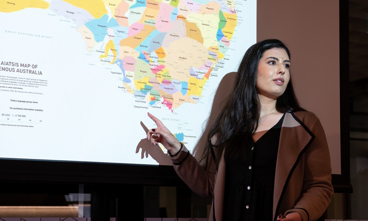 Woman addresses the room in front of a map of Australia