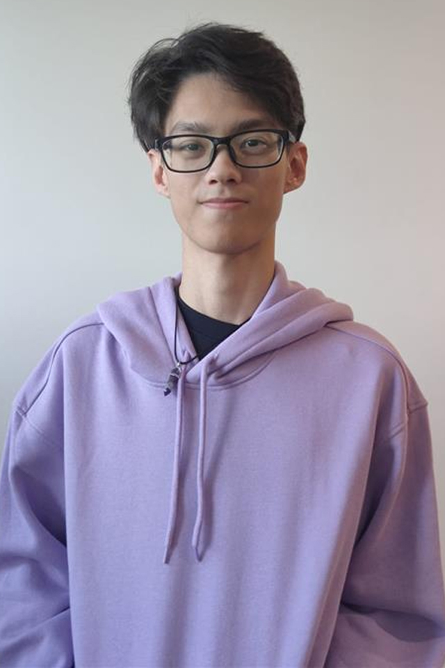 A portrait of a young Indonesian man wearing a purple hoodie and black glasses.