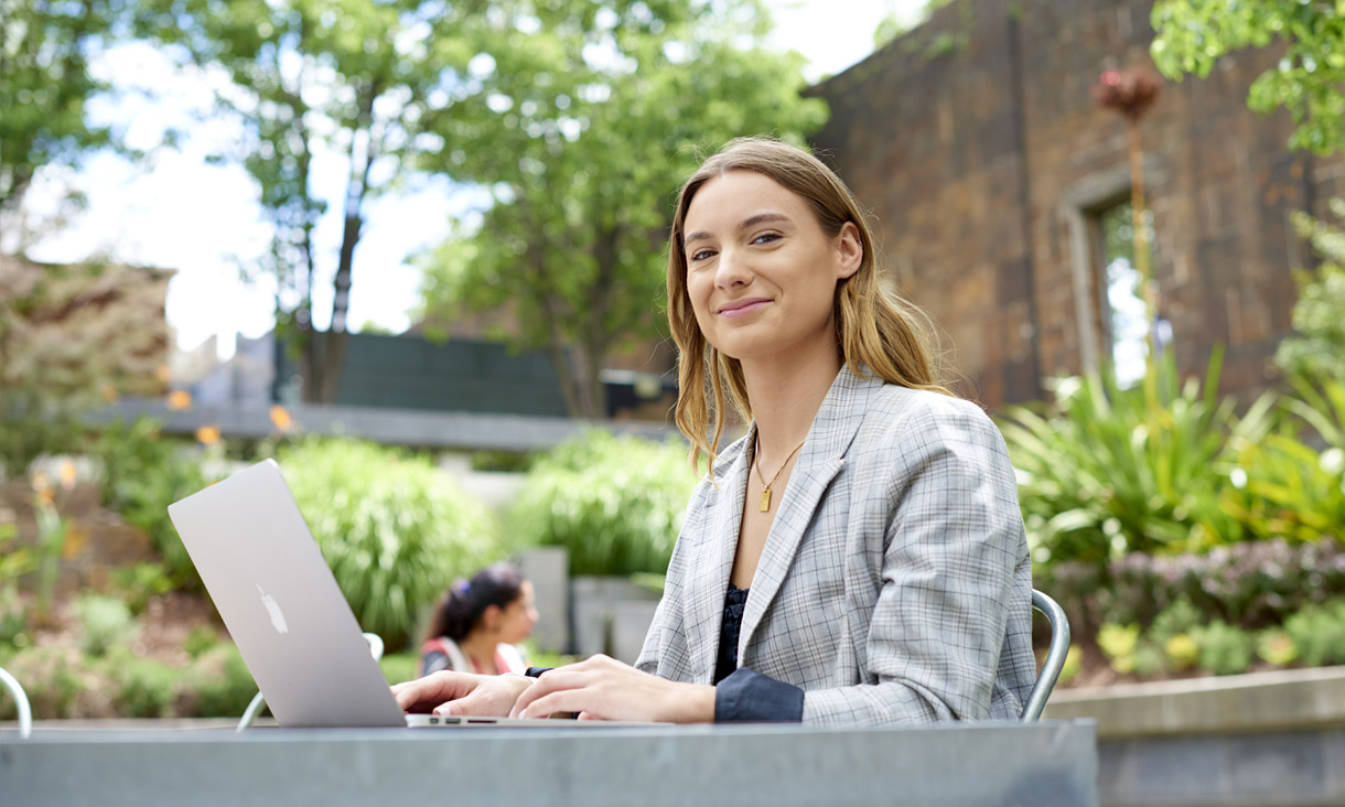 Public relations student using laptop outdoors on campus