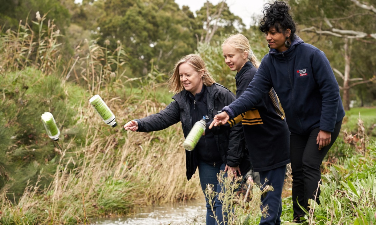 Melbourne Water’s Litter and Waterwatch Coordinator Naomi Dart, citizen scientist and Bentleigh West Primary School student Sophie Littlefair and RMIT’s Dr Kavitha Chinathamby launching GPS-tracked bottles into Dandenong Creek.