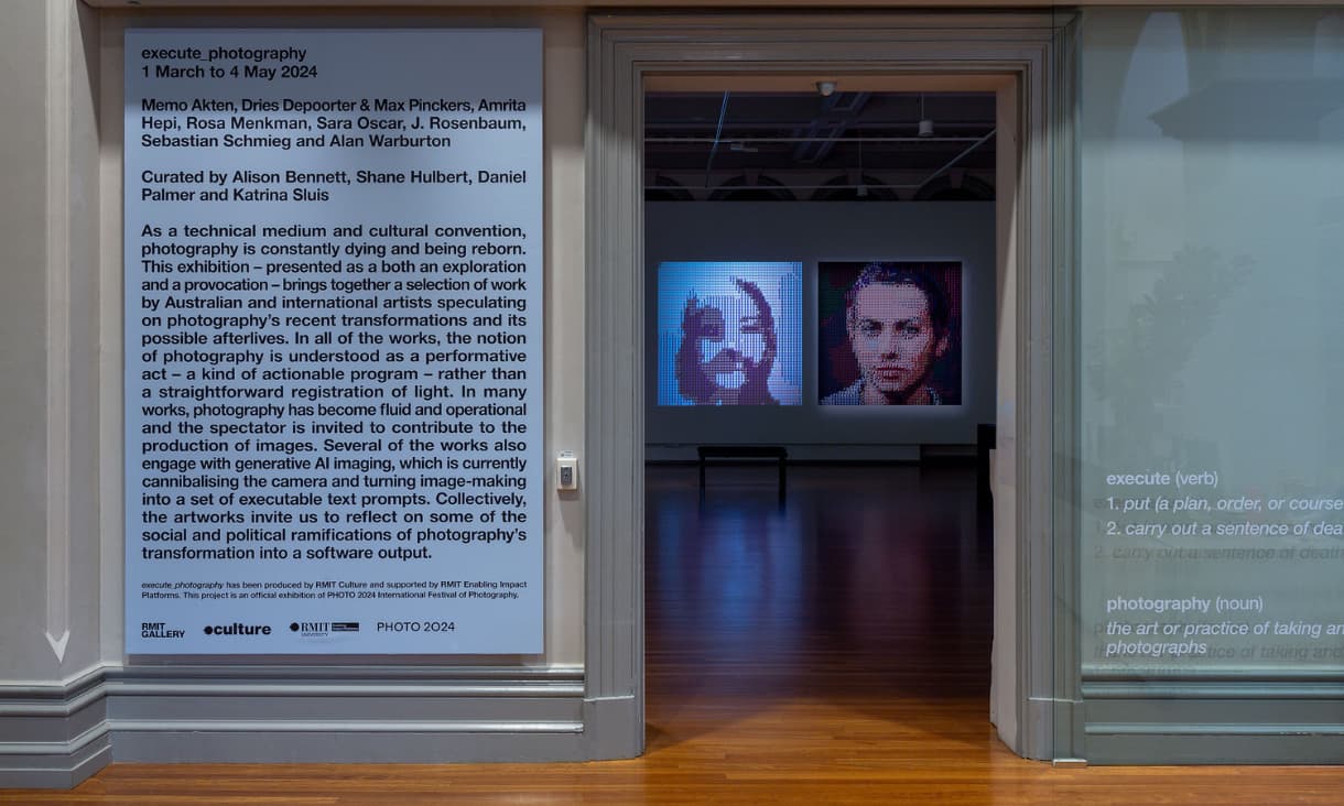 A doorway into a gallery exhibition with a text description on the left and the artwork through the doorwayin the distance