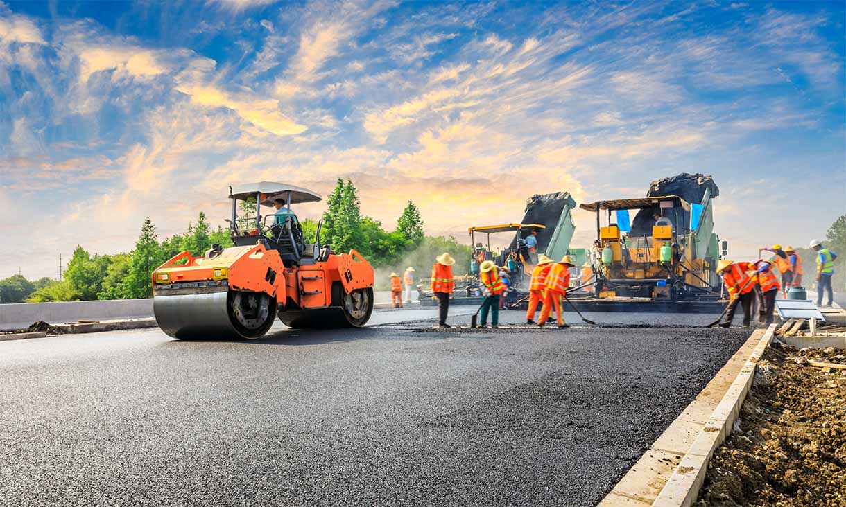 Road construction crew with machinery and workers laying new asphalt.