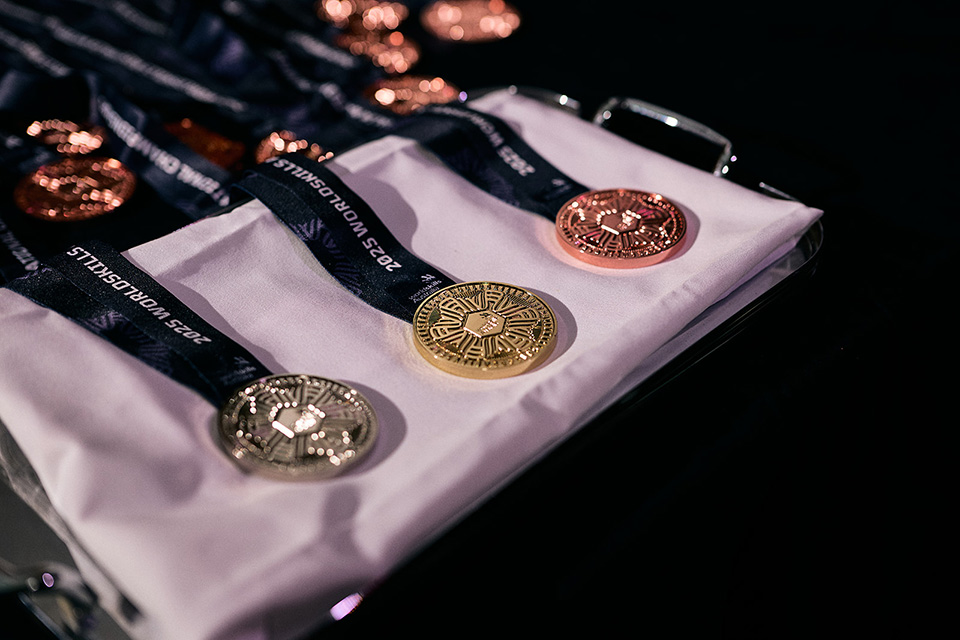Gold, silver, and bronze medals on ribbons labelled '2023 WorldSkills' are displayed on a tray with a white cloth.
