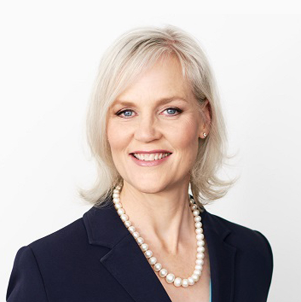 Philippa is smiling towards the camera against solid white background. Peggy is wearing a navy blue shirt.