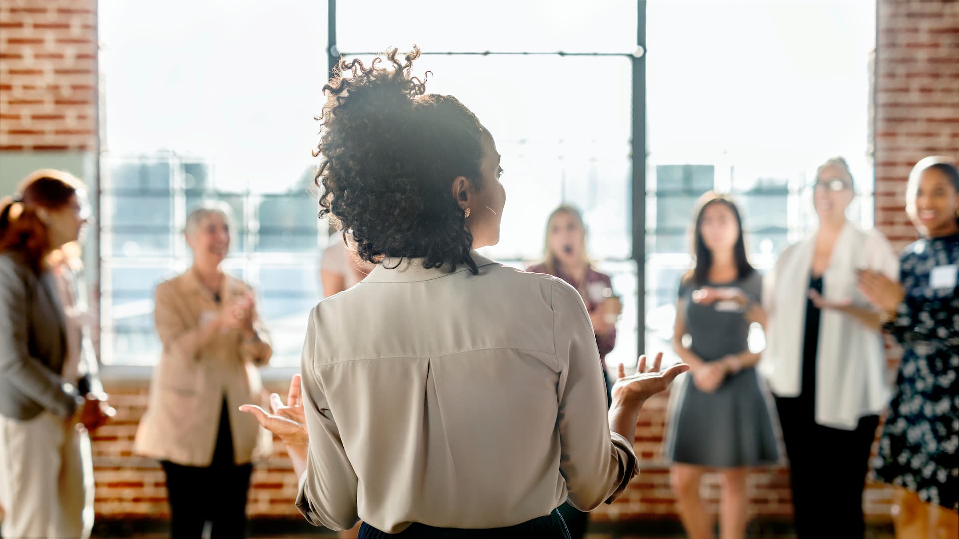 Person standing in front of blurred out circle of people with skyline in the window background