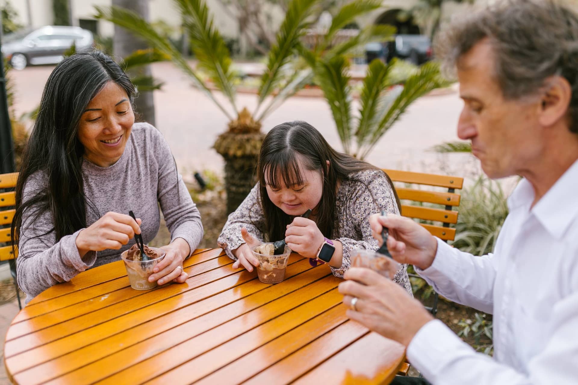 Two adults with young person eating sundaes outside