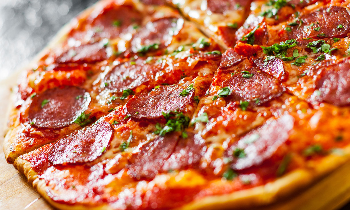 sliced Pepperoni Pizza with Mozzarella cheese, salami, Tomatoes, pepper, Spices and Fresh Basil. Italian pizza