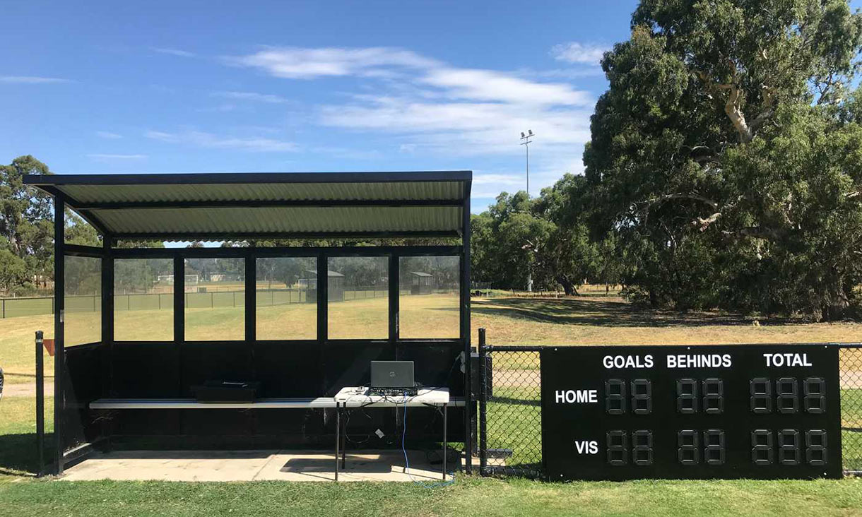 Scoreboard at football oval with trees in the background