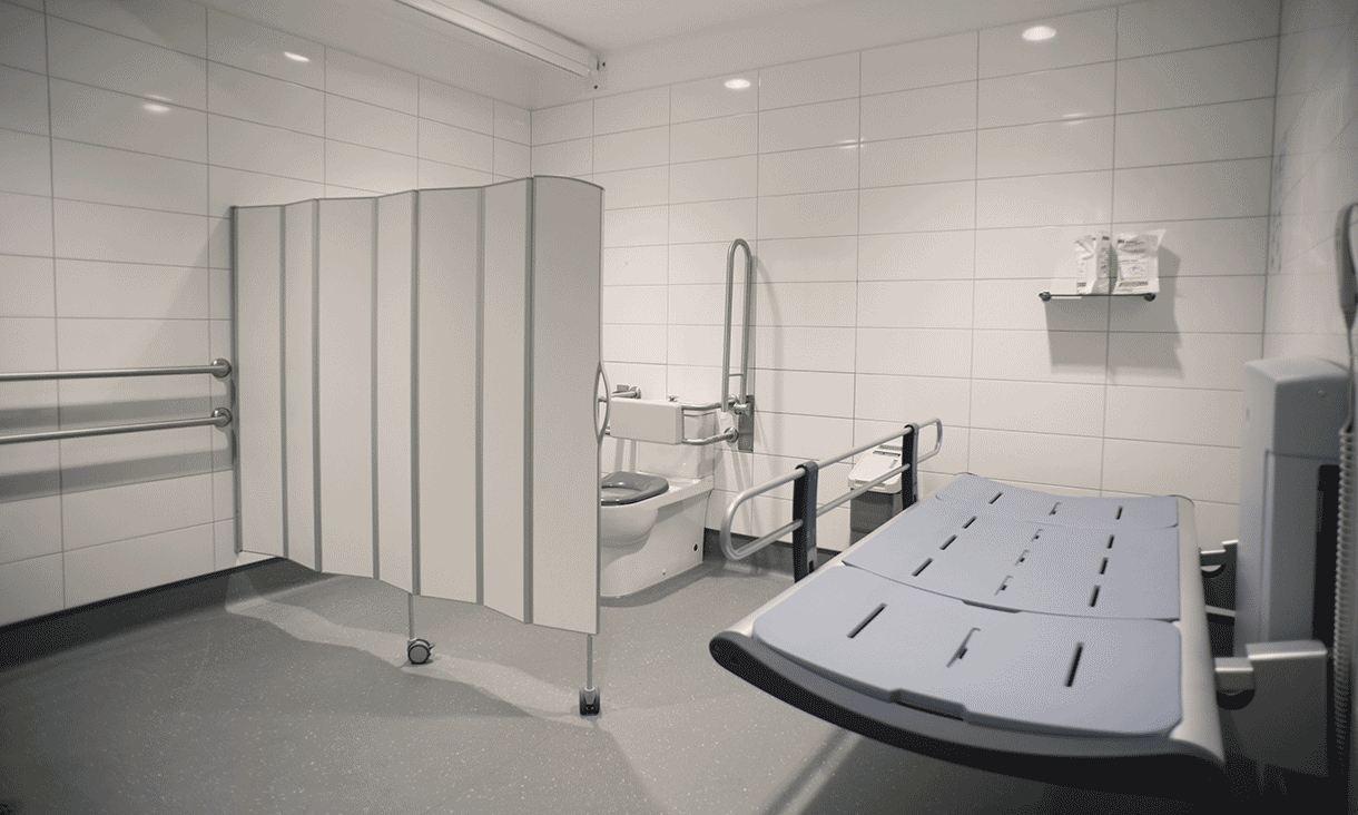 A changing room with a toilet and privacy screen