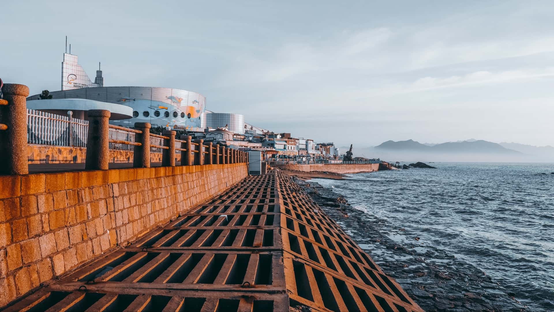 Buildings by an ocean with low mountains in the background