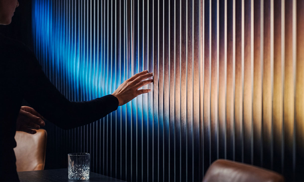 A person gently touching a wall featuring a bold, colorful striped pattern.