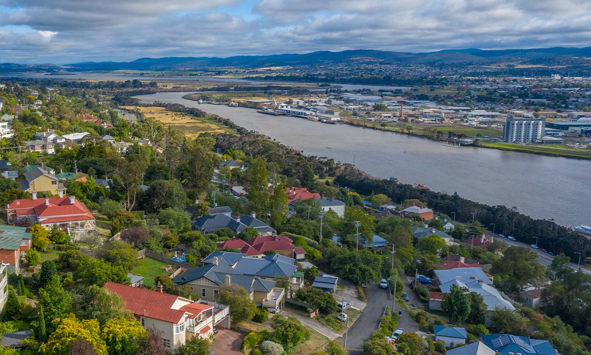 Aerial view of a city featuring residential houses and a winding river flowing through the landscape.