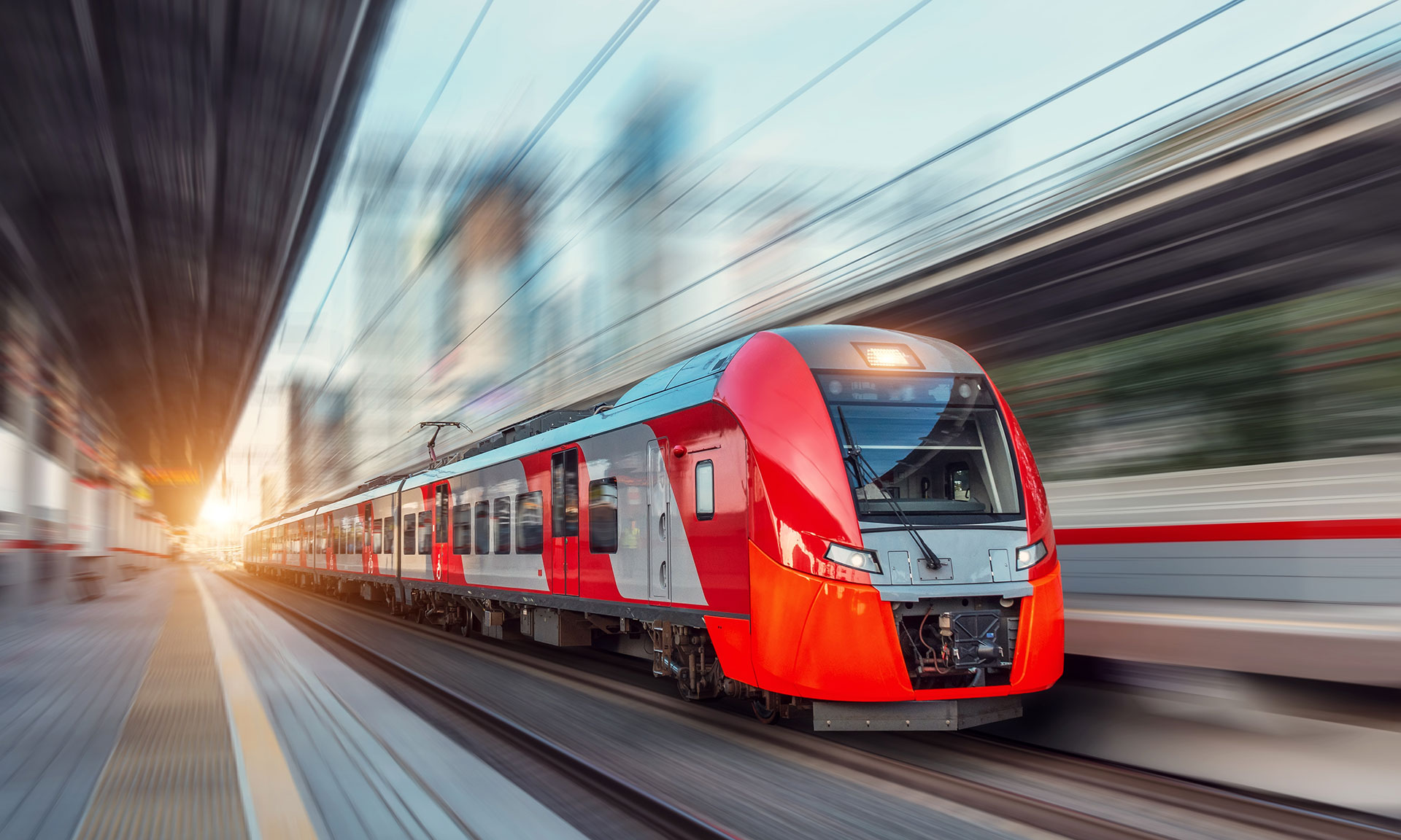 Electric passenger train drives at high speed among urban landscape