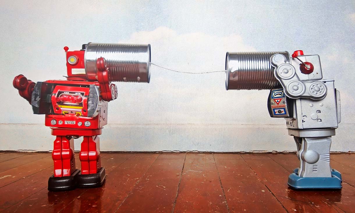 Two toy robots communicating through a tin-can telephone