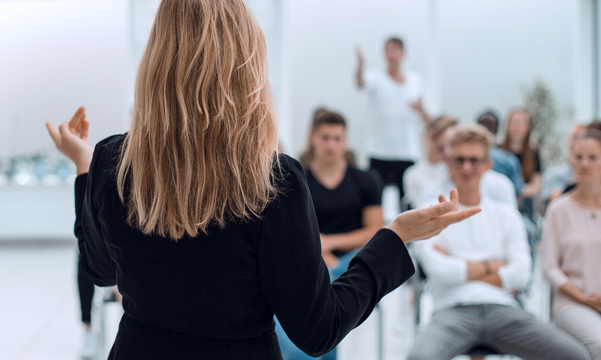 A female teacher standing in front of a class of adult students