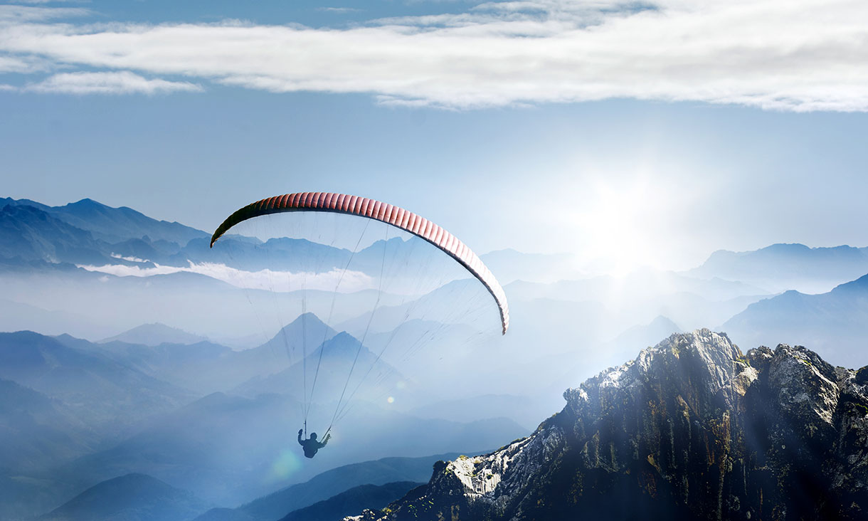 A paraglider sailing above a mountain range