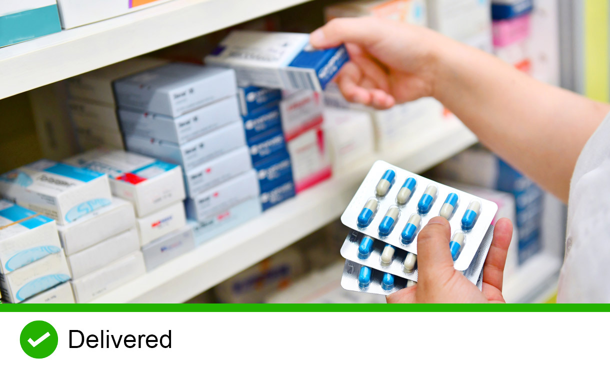 Pharmacist holding medicine box and capsule pack in pharmacy drugstore.