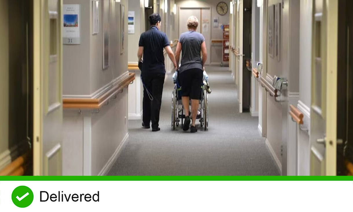 Person in wheelchair being pushed down a hallway