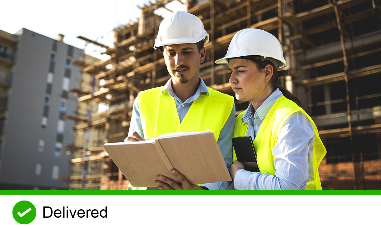 Two construction workers looking at a notebook