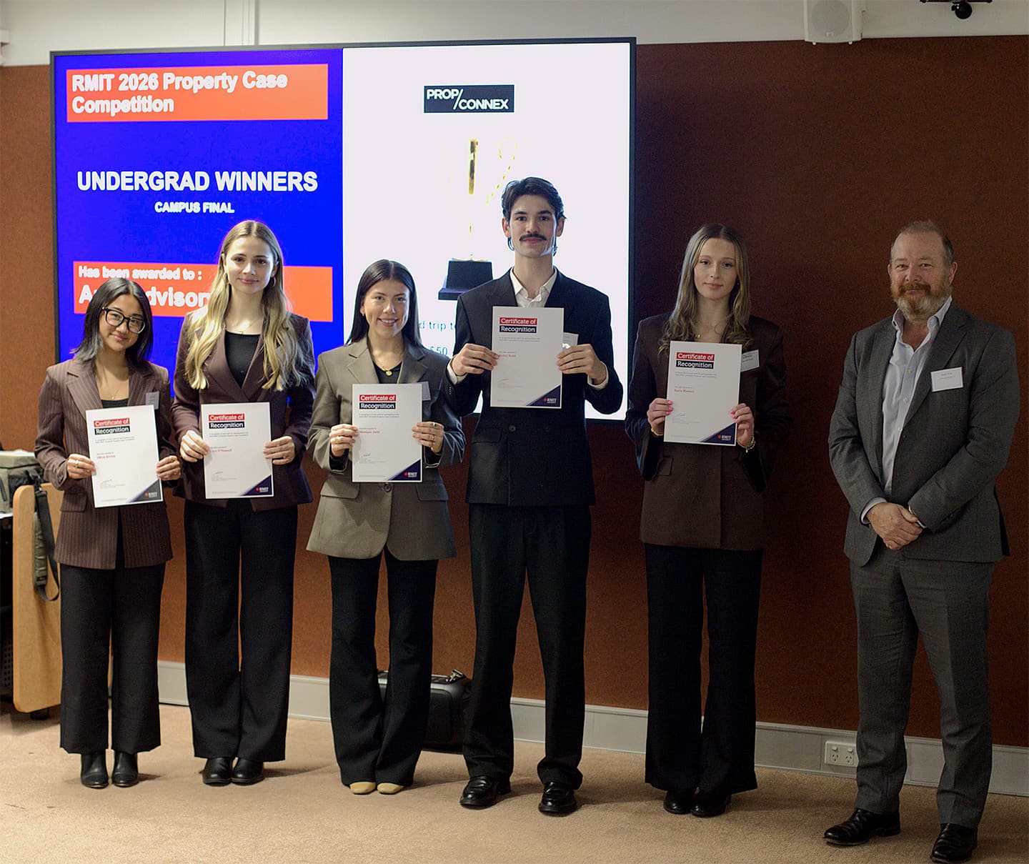 Five students of Property, Constuction and Project Management standing holding award certificates next to a lecturer.