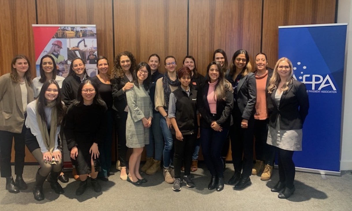 attendees at the WOMENG breakfast posting for a group photo in front of AFPA and program banners
