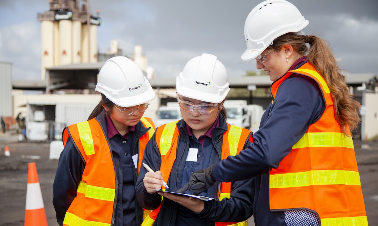 group of female high school students wearing high vis vests and hard hats on excursion at asphalt plant