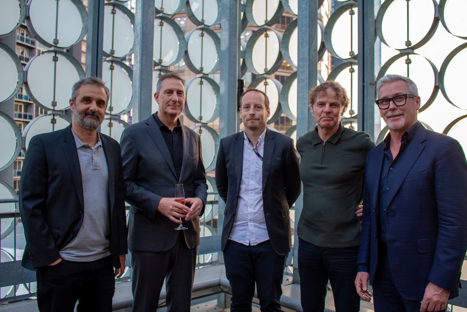 five men standing on the rooftop of RMIT’s Design Hub with the sun setting in the background.