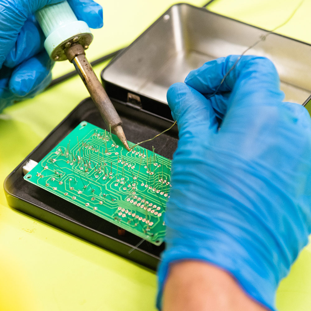 Gloved hands working on an electrical board