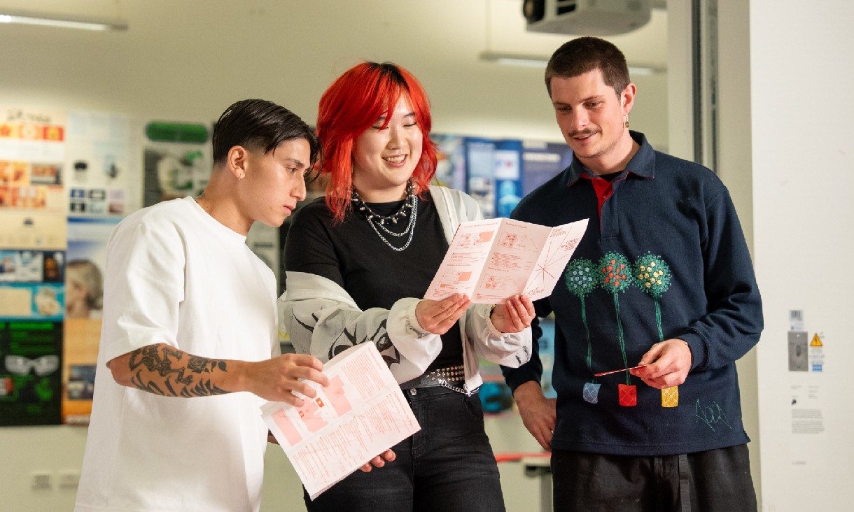 Three students looking at information sheets.