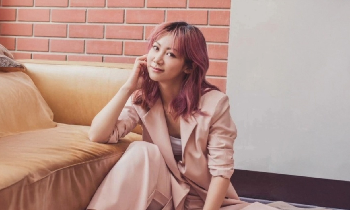 Jenny poses for the camera with a hand on her cheek.