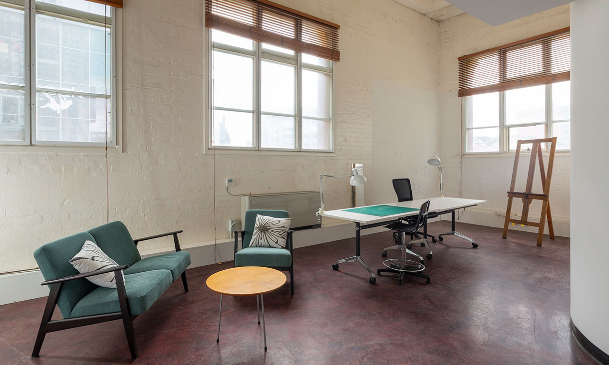 Studio with a lounge, lounge chair, desk, small table and an easel.
