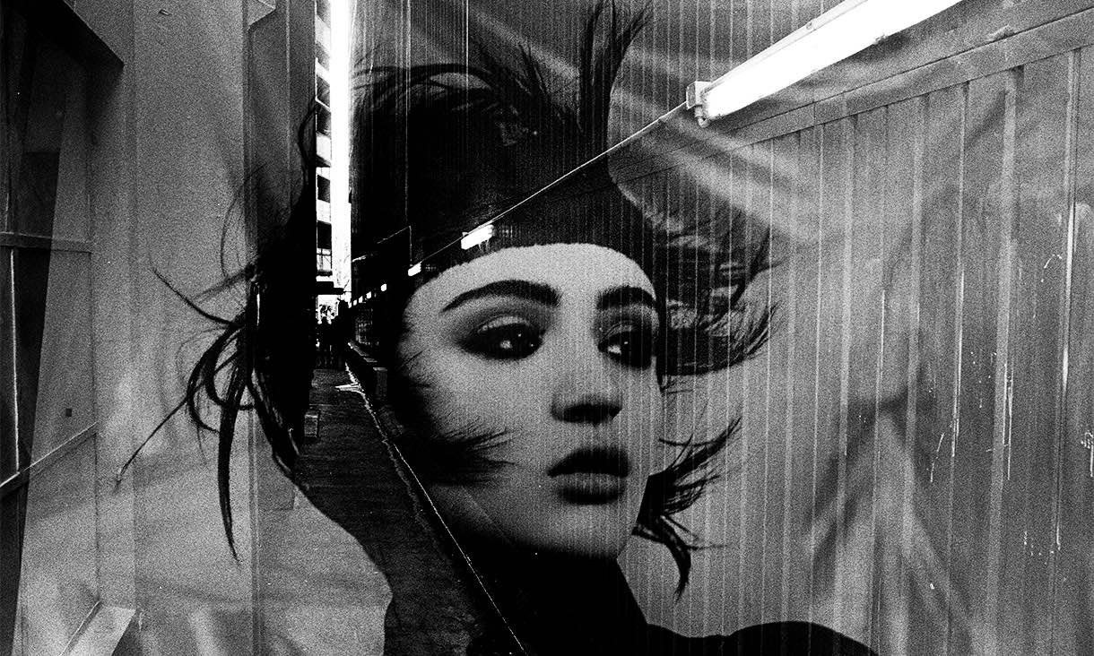 black and white photo of female face superimposed on a narrow laneway