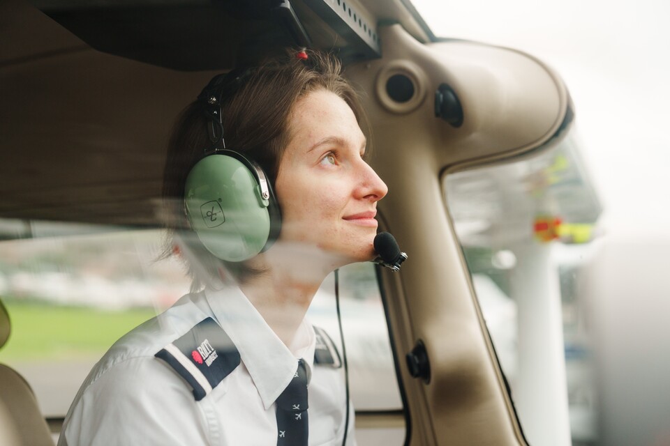 A young pilot in a plane cockpit looks up at the sky. 