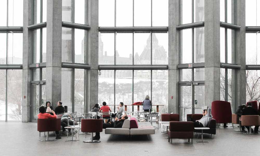 People sitting on couches in large building by the windows