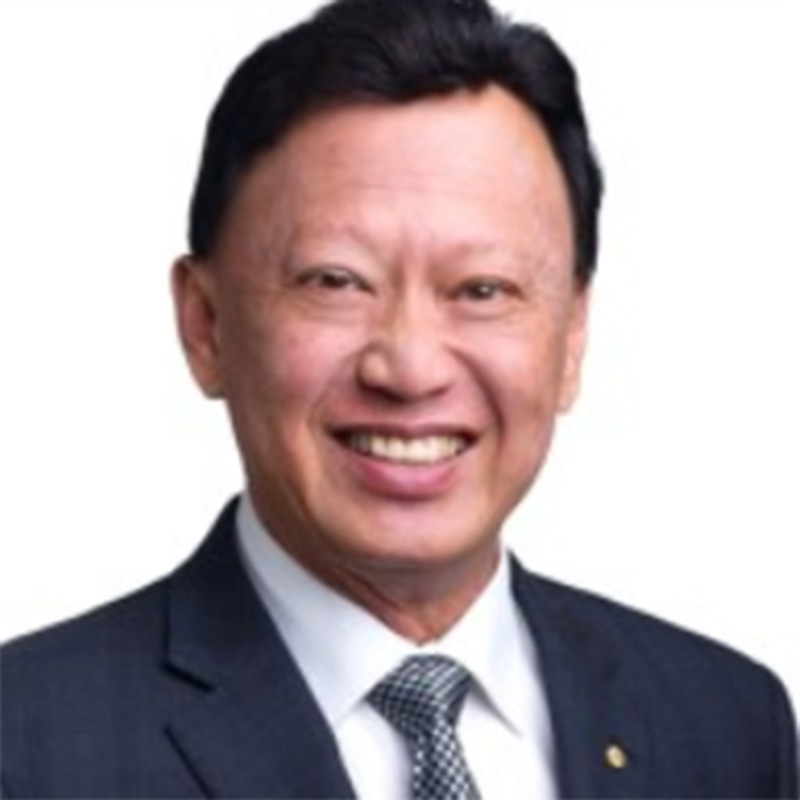 Photograph of Francis. He smiles directly at the camera. He has short, black hair and wears a dark suit with a silver checkered tie.