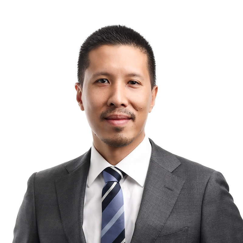 Photograph of Khunapong. He smiles directly at the camera. He has short, black hair and wears a grey suit with a blue striped tie.