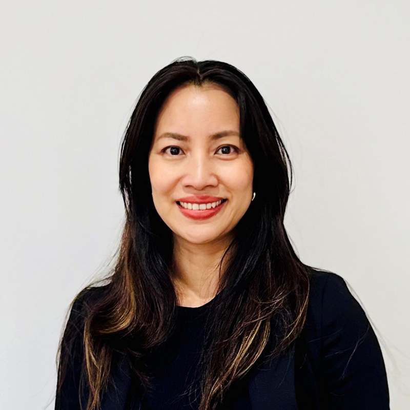 Photograph of Mihn Cao smiling directly at the camera. She has long, black hair and wears a black shirt.