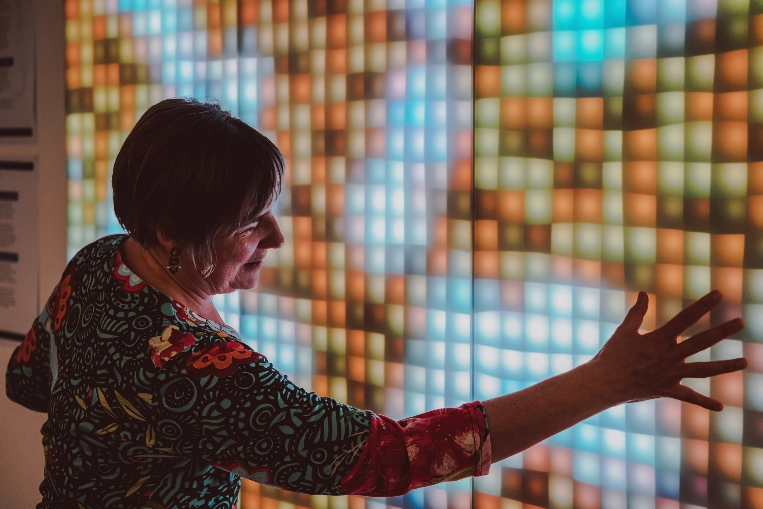 Women reaches for a screen of different coloured squares.