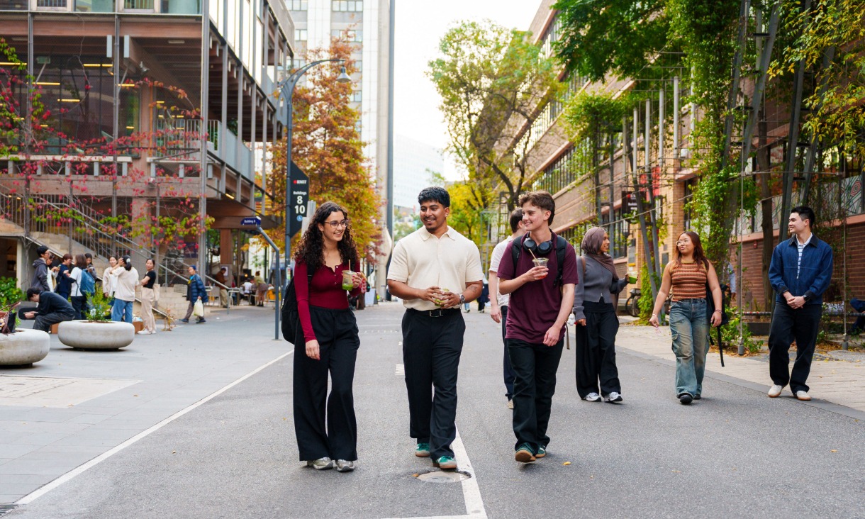 Three students walking down a university street in coversation.
