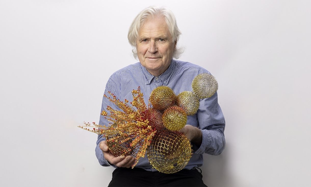 Portrait of Robert Baines holding his work, Three Spheres and the Collision, 2024-25, silver, electroplate, lacquer. Image courtesy of the artist. Photo: Joanne Manariti