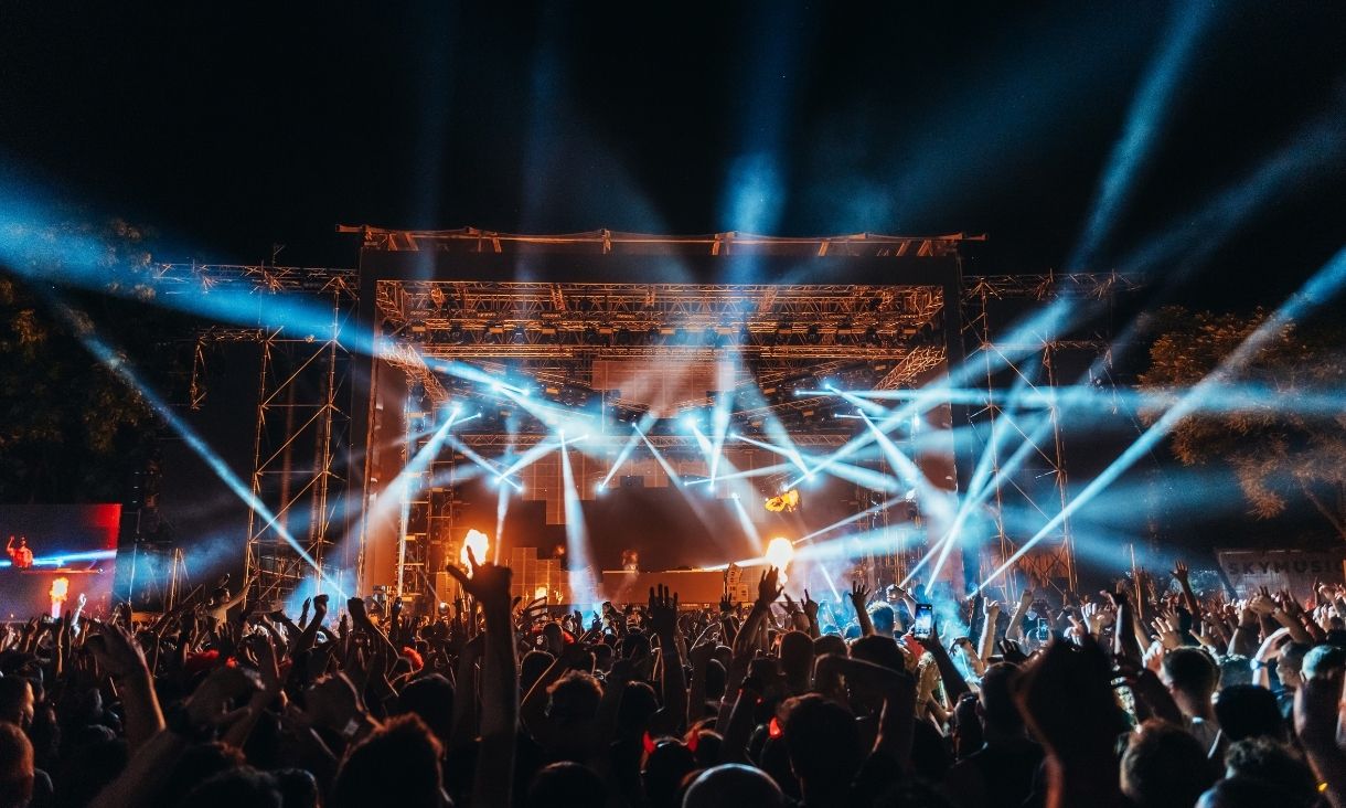 Silhouettes of concert crowd in front of bright stage lights on a music festival