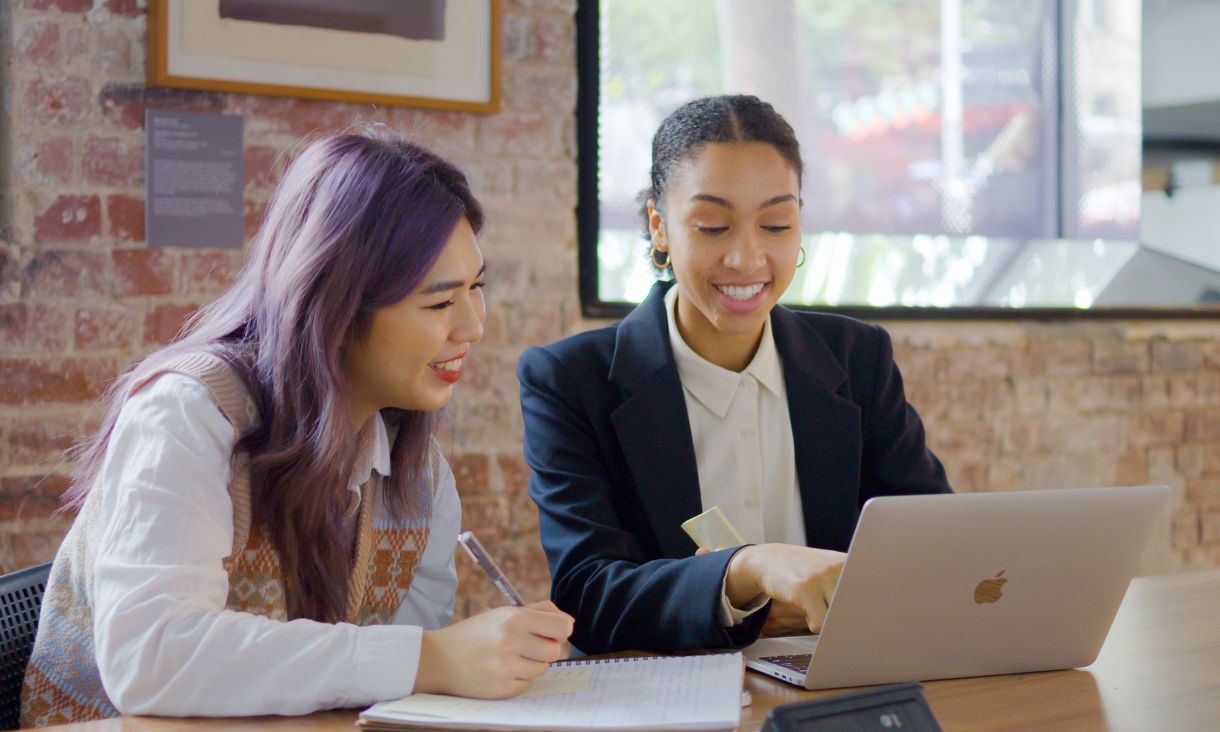 two women smiling at a computer