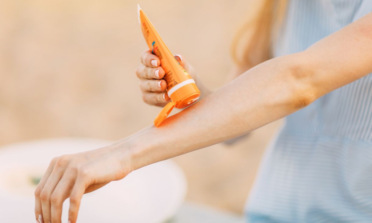 Hand putting sunscreen on a persons arm
