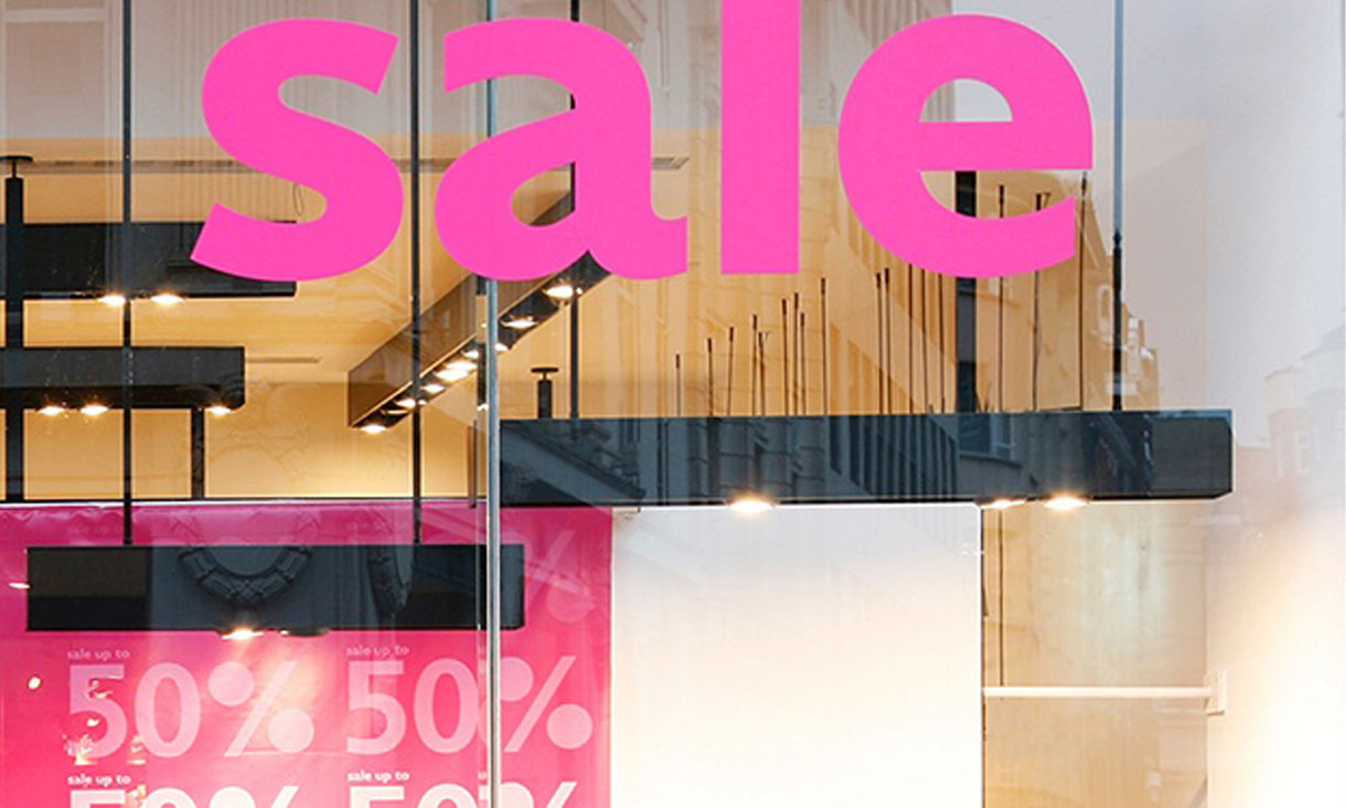 A storefront with sale decals on the windows and a 50% banner in the window.