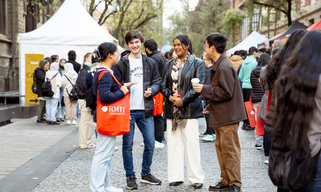 Four diverse international students smiling and chatting at a university open day.