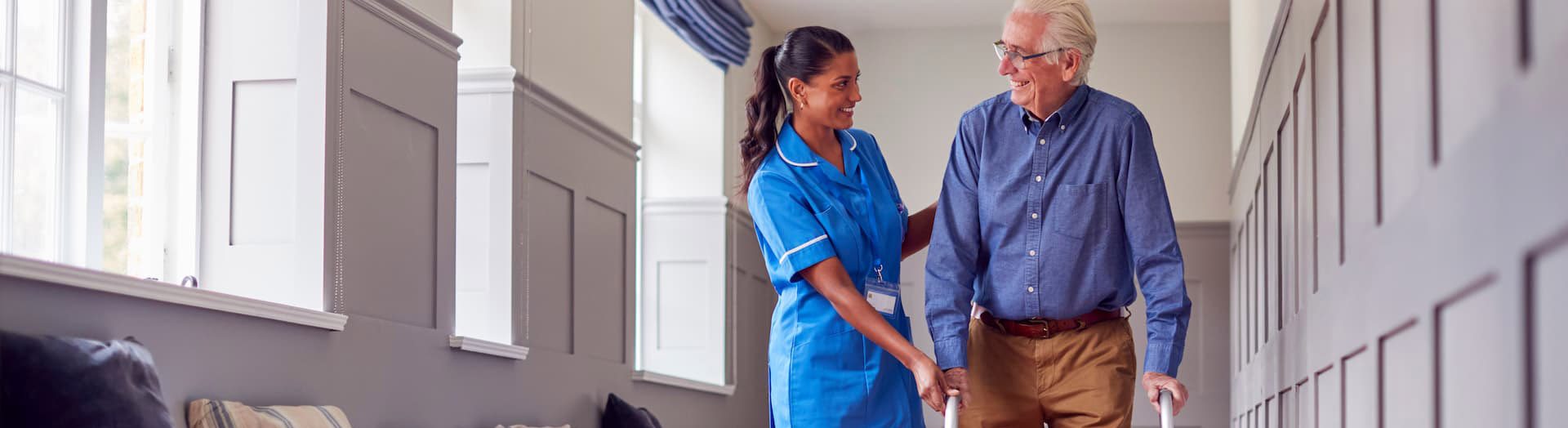 Nurse helping elderly person using a walker