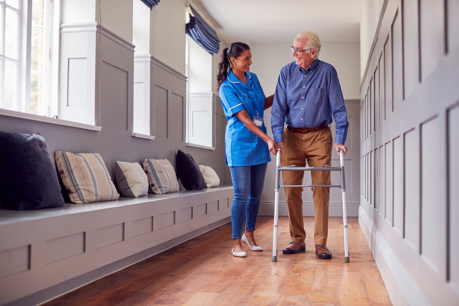Nurse helping elderly person using a walker